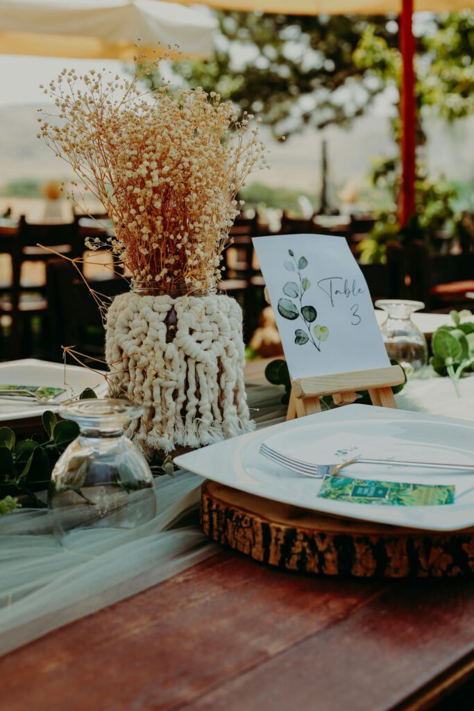 Beautiful outdoor dining table with dry floral centerpiece and greenery accents.