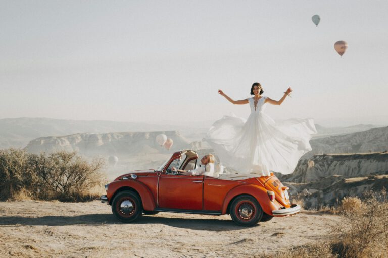 Bride and groom celebrating their wedding atop a vintage car in Cappadocia, Turkey.