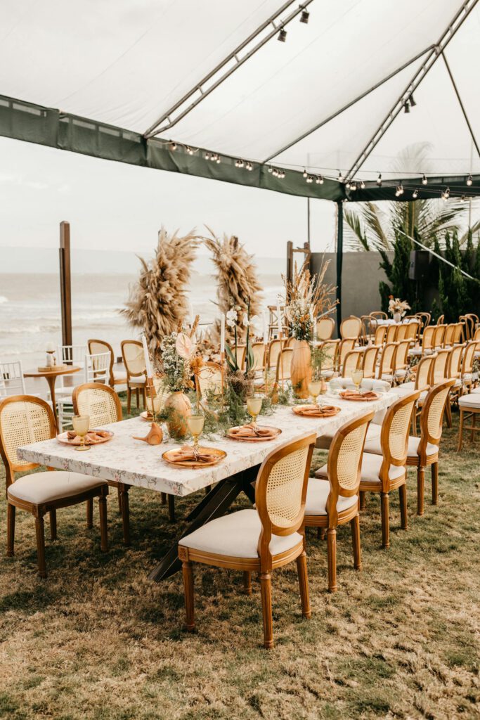 Stylish outdoor dining setup on a beachfront, featuring elegant decor and natural elements.